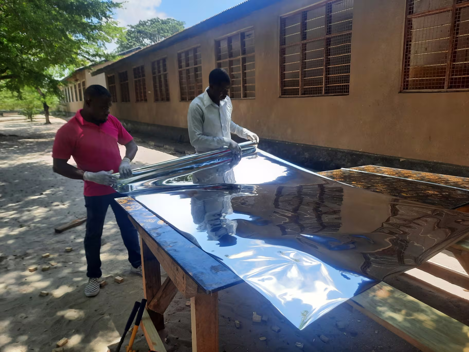 Reflective aluminium sheeting being prepared outside a classroom in Dar es Salaam