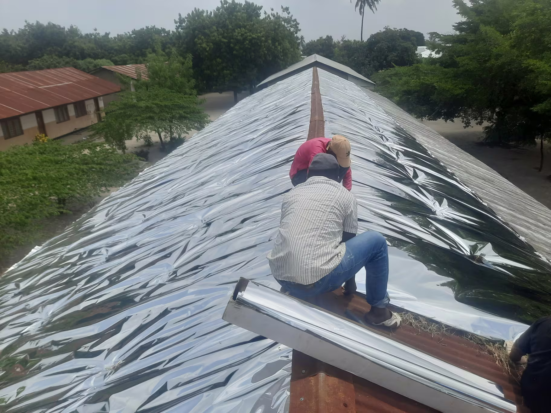 A completed ridge of reflective aluminium sheeting across a school block