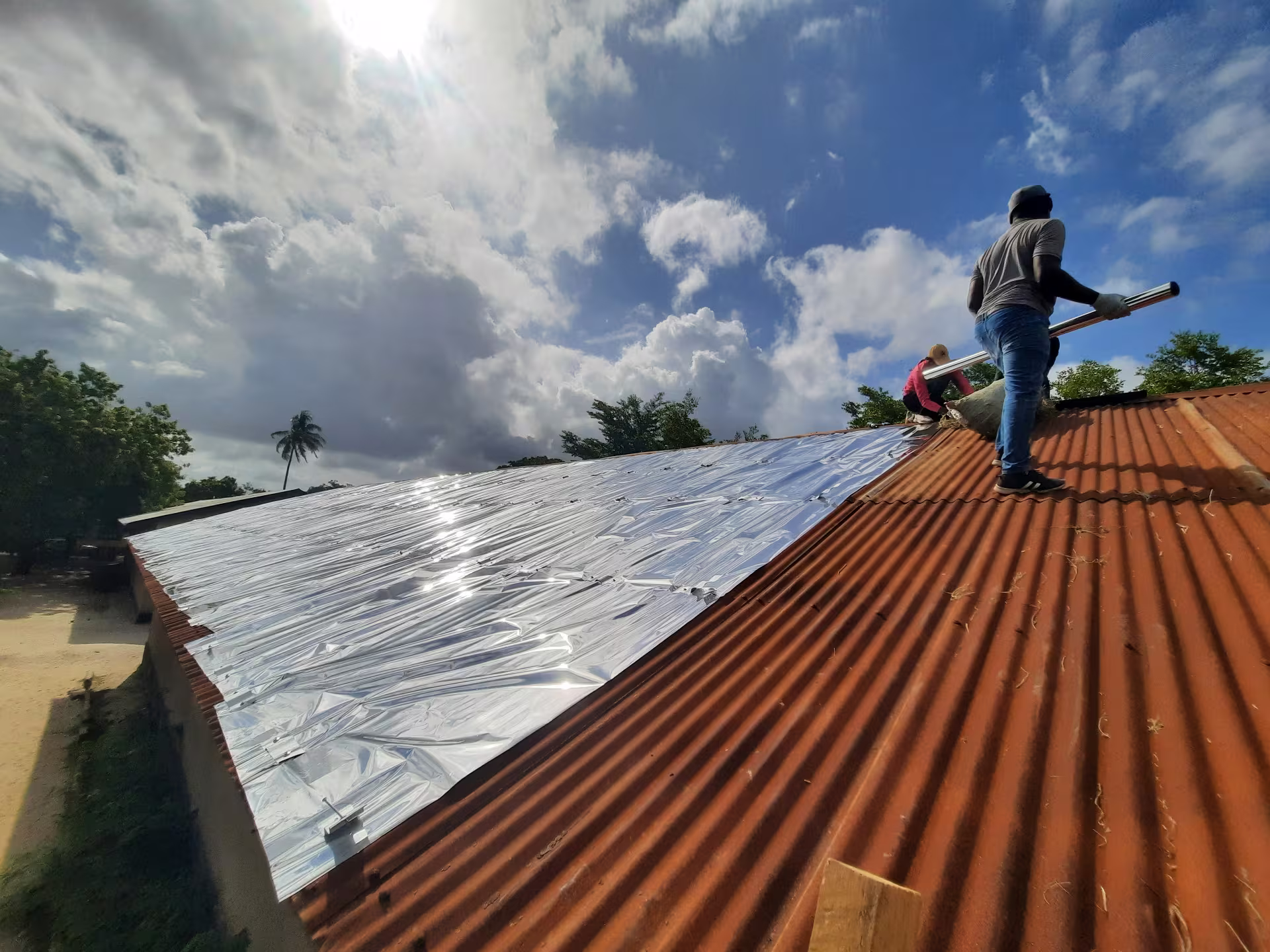 Installation d'un toit réfléchissant en cours sur un bâtiment résidentiel.